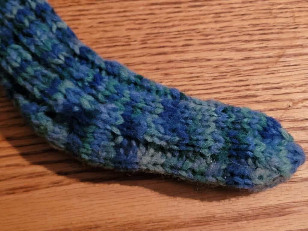 blue and green knitted sock showing variegated colors when dye as a skein